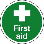 This photo features a round, anti-slip laminated floor sign with the words First Aid in bold letters. The sign is designed by Spectrum Industrial and is part of their collection of first aid signs. The colors are bright and eye-catching, making it easy to spot in an emergency. The size of the sign is 400mm in diameter and it is specifically designed for use on floors.
