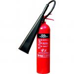 This photograph captures a 5kg CO2 fire extinguisher from Sentura Group in action. The bright red cylinder sits upright on the ground, with its handle ready to be pulled in case of emergency. A white label displays safety instructions and specifications. The extinguisher is surrounded by a bright yellow protective casing with a bold Fire Extinguisher label. Visible through the casing is the pressure gauge, indicating that the extinguisher is fully charged and ready for use. In the background, a small fire can be seen being snuffed out by the powerful CO2 spray.