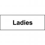 In the photograph, there are several compact and modern-looking industrial washroom signs. Each one measures 300 x 100mm and is made of 1.2mm recyclable PP. The signs are specifically for indicating the ladies washroom, and they have a bold and clear Ladies label in white against a dark grey background. The signs feature the iconic female figure symbol, also in white, on the right side. The overall aesthetic is sleek and professional, perfect for any industrial setting.