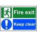 The photograph shows a bright red Spectrum Industrial Fire Safety Sign with bold, white lettering that reads Fire Exit Keep Clear on a 1.2mm thick, recyclable PP material. The sign measures 300 x 200mm and features a universal fire exit symbol. The sturdy construction and clear messaging make it an essential addition to any industrial setting to ensure the safety of all.