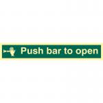The picture shows a vibrant red and white industrial fire safety sign with the words Push Bar To Open in bold letters. The flexible vinyl material allows for easy installation. The sign glows in the dark due to its photoluminescent properties, making it visible during emergencies. It measures 450mm x 100mm.