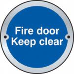 This photograph captures a set of Spectrum Industrial room signs featuring a Fire Door Keep Clear message. Made of sleek satin stainless steel, the circular disc measures 75mm in diameter. These signs are designed to keep emergency exits clearly marked and easily accessible.