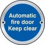 The photo depicts a set of Spectrum industrial room signs for automatic fire doors. Made of satin stainless steel, each sign features a clear keep clear door disc with a diameter of 75mm. These signs are a practical and professional addition to any industrial setting.