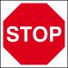 The image shows a Spectrum Industrial road with traffic signs, including a red stop sign. The sign is made of 3mm Foamex board and measures 400mm x 400mm. Bright colors and clear text make it easily visible for drivers on the road.