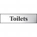 The photograph shows a sleek and modern-looking Spectrum Industrial Washroom Signs Toilets Sign. It features a chrome effect and is made of self-adhesive PVC, measuring 200mm x 50mm. The sign is perfect for any industrial or commercial restroom setting with its clean design and easy installation.