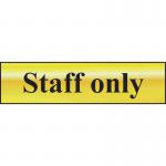 This photograph is a close-up of a Spectrum Industrial Room Signs Staff Only Sign. The sign is made of polished gold effect metal and measures 200mm x 50mm. It is self-adhesive and made of PVC material. The sign features bold, easy to read text and a sleek, professional design. The sign is perfect for indicating restricted access areas in a workplace or commercial setting.