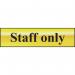 This photograph is a close-up of a Spectrum Industrial Room Signs Staff Only Sign. The sign is made of polished gold effect metal and measures 200mm x 50mm. It is self-adhesive and made of PVC material. The sign features bold, easy to read text and a sleek, professional design. The sign is perfect for indicating restricted access areas in a workplace or commercial setting.