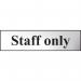 The photograph shows a sleek Spectrum Industrial Room Signs Staff Only Sign. It is chrome effect and made of self-adhesive PVC. This rectangular sign measures 200mm x 50mm and is perfect for professional or industrial spaces. Its bold lettering and sharp edges are easy to read and stand out.