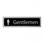 The photograph features a sleek black and chrome washroom sign designed for gentlemen. The sign measures 200mm x 50mm and has a polished finish. The letters are bold and clearly visible against the dark background. The design exudes a professional and modern aesthetic.