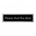 This photograph features a rectangular industrial room sign from Spectrum with the message Please shut the door printed in bold letters. The sign measures 200 x 50mm and has a blue background with white text. The CHR design adds a modern touch to the sign, making it suitable for various industrial settings.