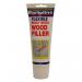 The photo shows a 330gm tube of white wood filler from Bartoline Limited Tools, labeled with product information and a logo. The tube is filled with a creamy white substance, ready to be used for filling cracks and holes in wood.