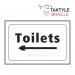 The Spectrum Industrial washroom signs are self-adhesive and feature a directional arrow pointing left. The signs are designed for toilets and are in a crisp white color. The dimensions are 225mm x 150mm.